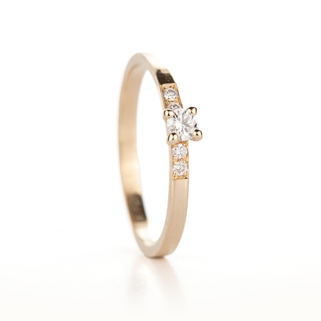 Een geelgouden verlovingsring met een diamant en kleine diamantjes