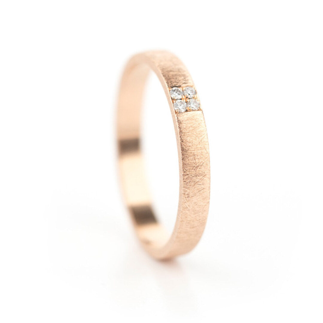Een brede geborstelde roodgouden ring met vier kleine diamantjes