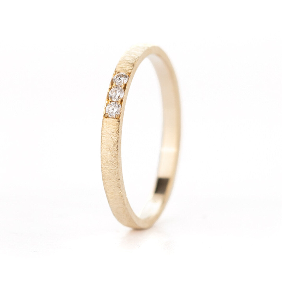 Een smalle geelgouden ring met drie kleine diamantjes