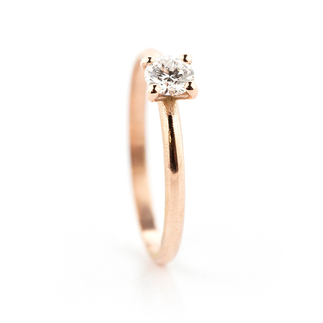 Een roodgouden verlovingsring met één diamant op een bolle band